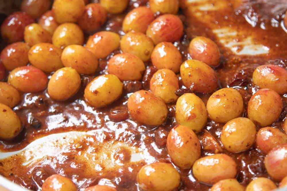 Grapes in a skillet cooked all the way through to where the color has changed drastically.