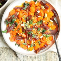 Honey Butter-Glazed Carrot Recipe garnished with sliced dates, basil, and pistachios.