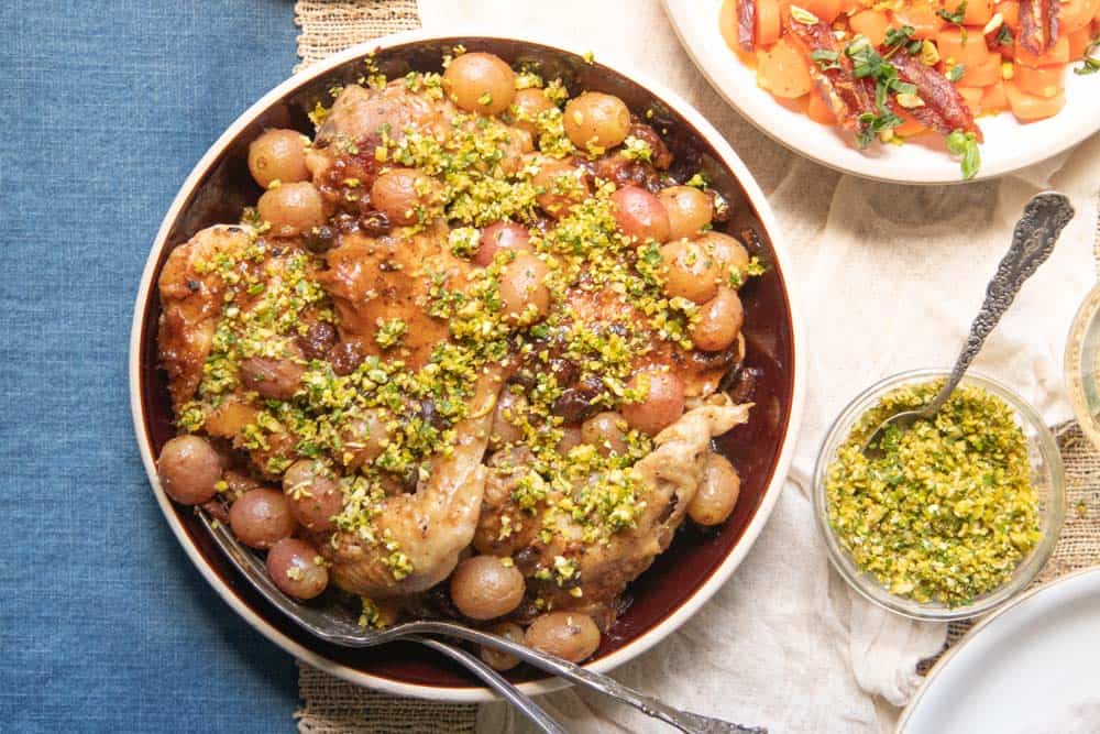 A serving dish of our favorite Chicken Recipe with Wine, Grapes, and Raisins topped with gremolata.
