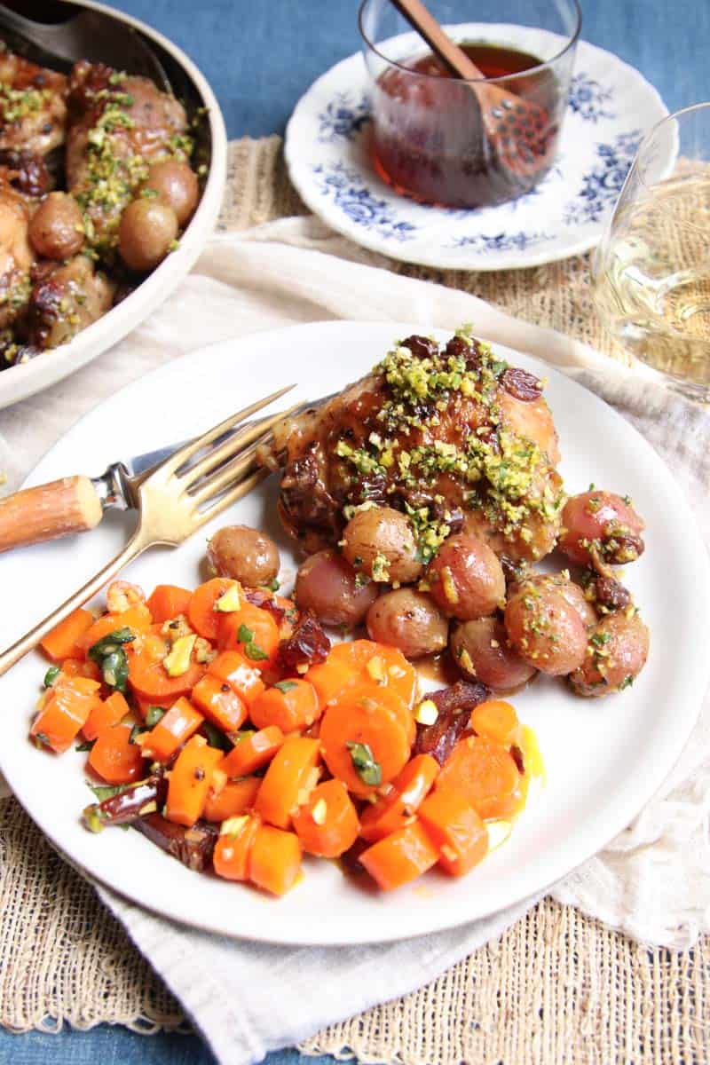 A serving plate of chicken with grapes and gremolata and carrots.
