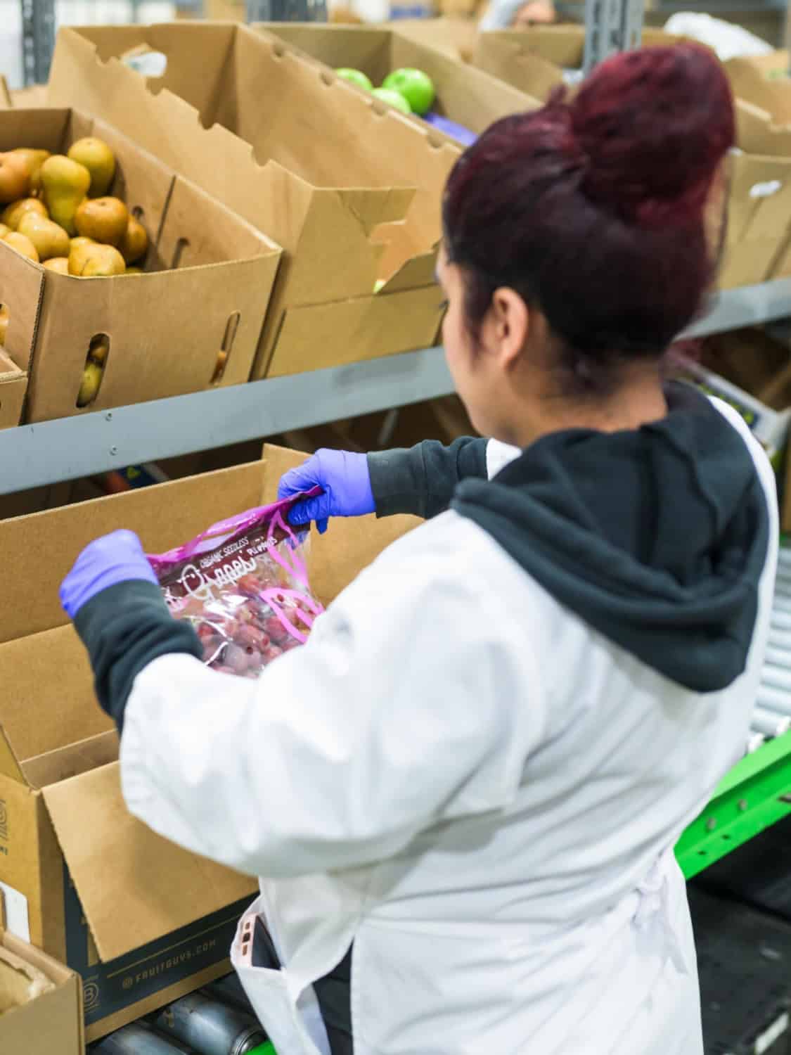 The Fruit Guys carefully inspecting produce before putting it in the box
