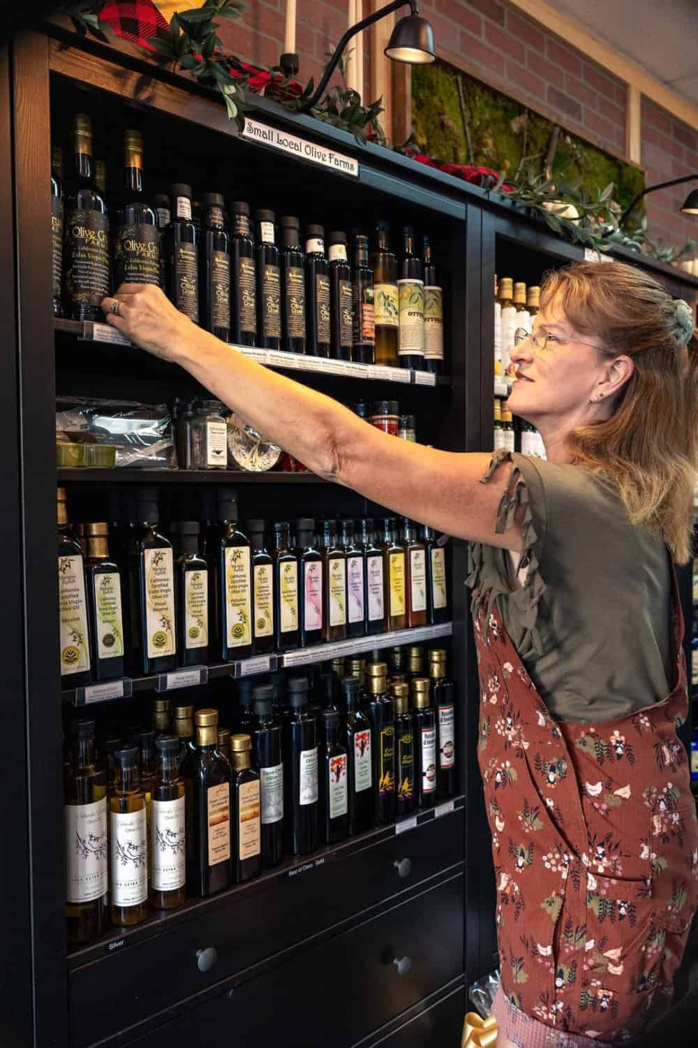 woman reaching for CA GROWN olive oil on a shelf