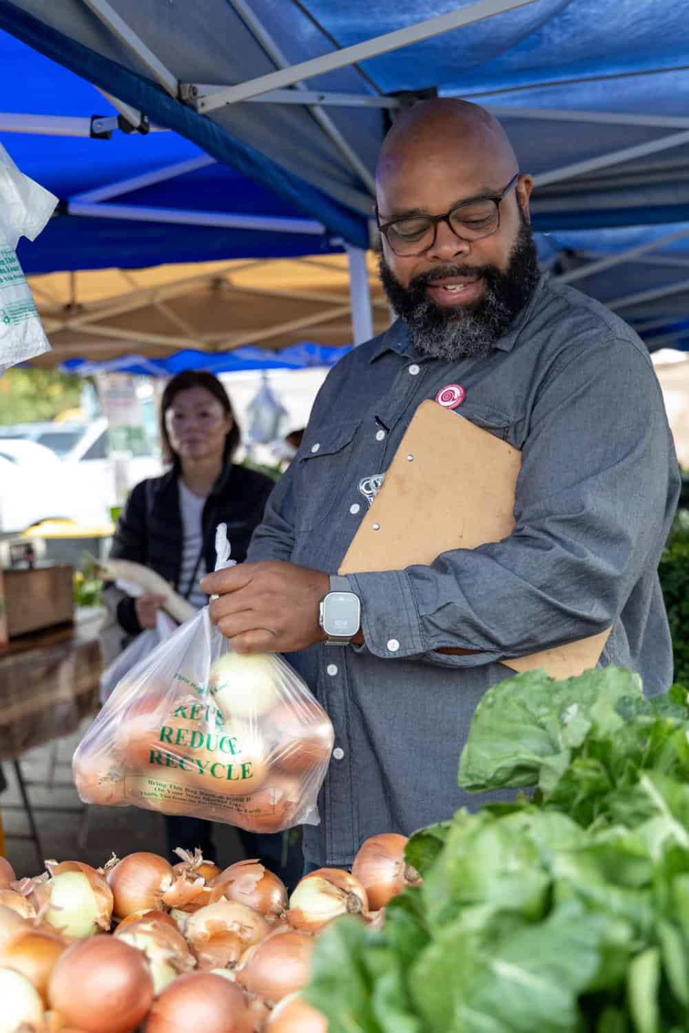 Chef Dennis Sydnor adding onions to a bag at Florian Farmers Market