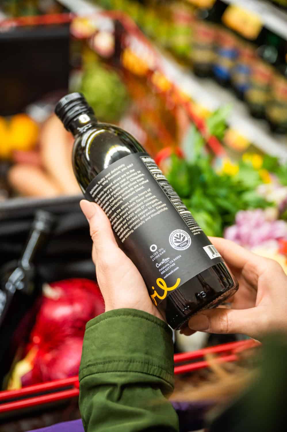 woman inspecting a bottle of CA GROWN olive oil with the label