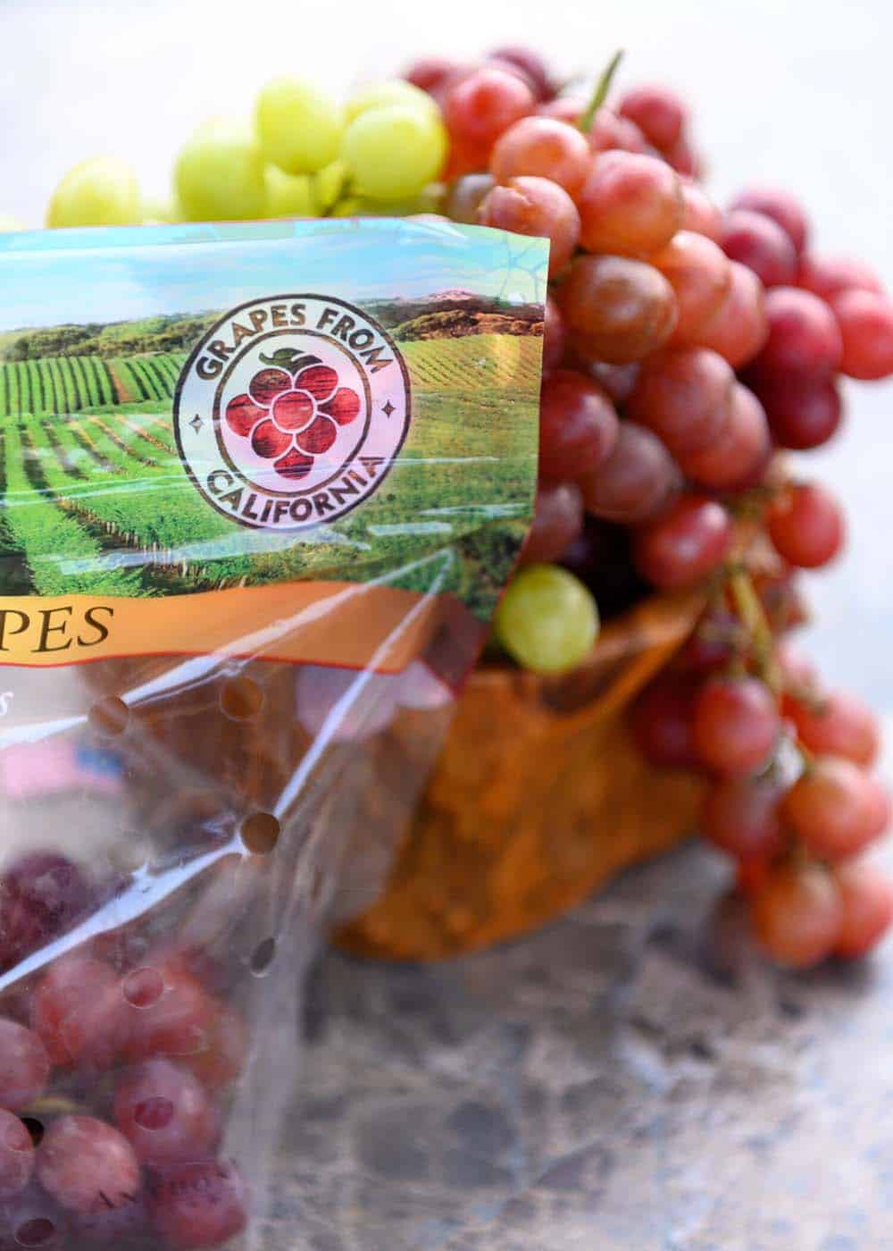 A bag of California grapes with red and green grapes in the background.