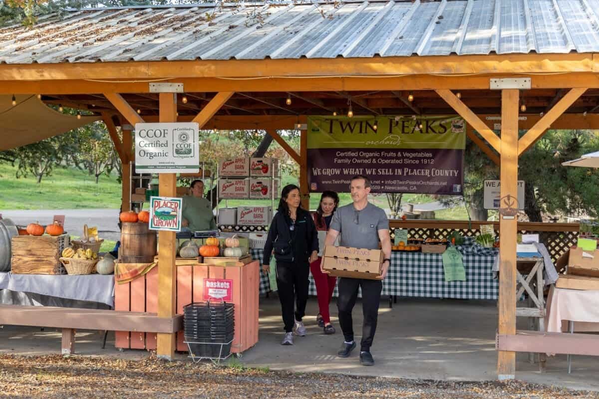 family walking out of Twin Peaks Orchards farmstand with fruit in hand