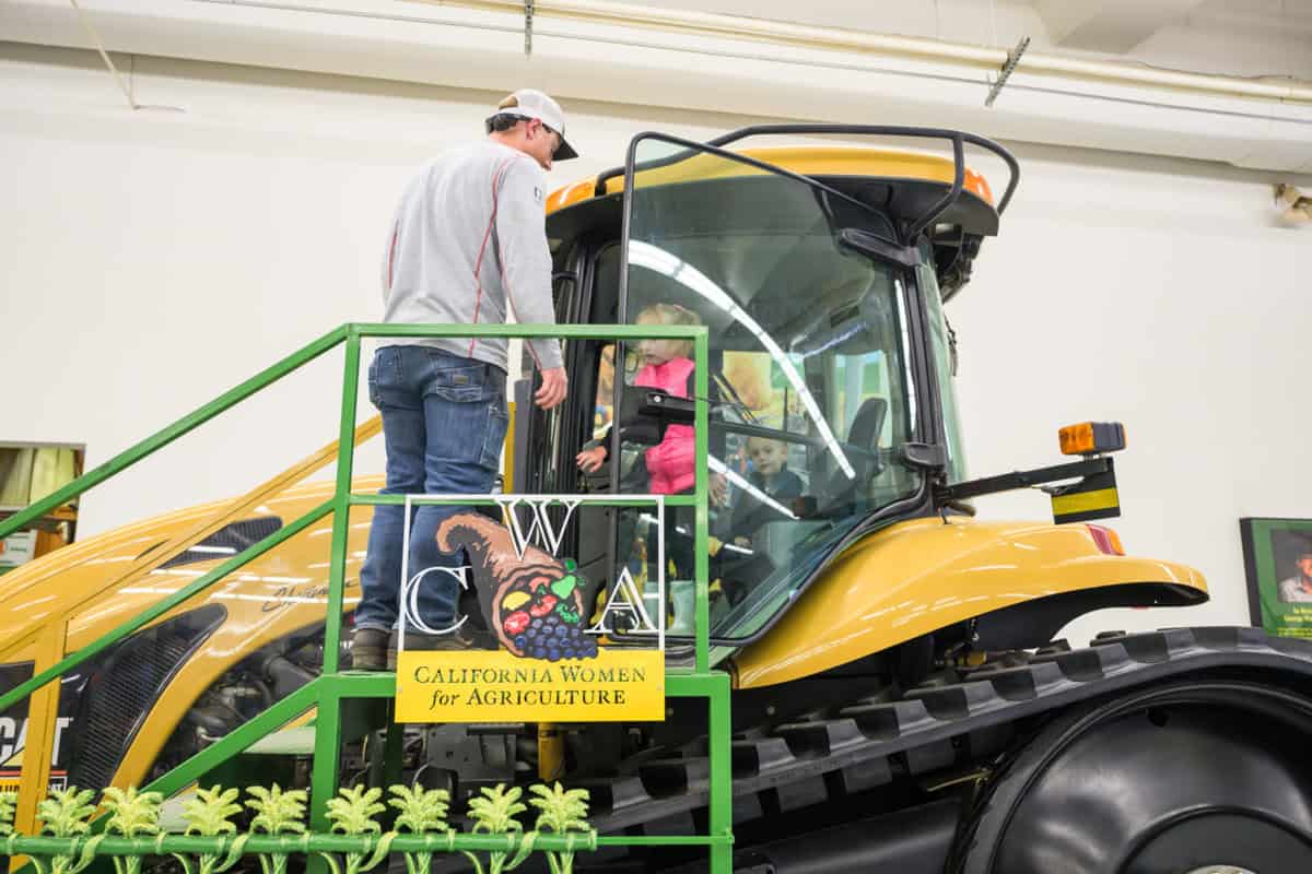 A child playing on the inside of a tractor at World Ag Expo