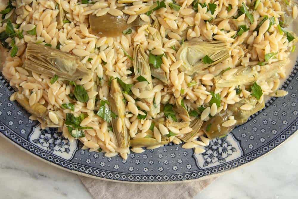 Close up of orzo salad with baby artichokes before adding walnut breadcrumb mixture.