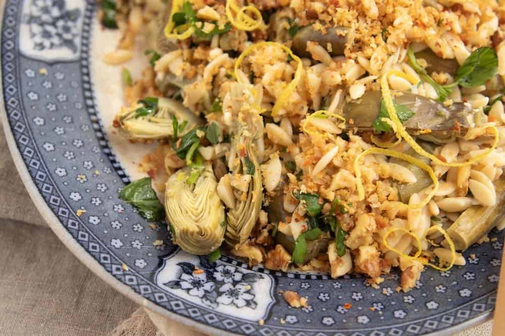 Close up of orzo salad focusing on steamed artichoke hearts.