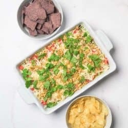 California Dreaming 8-Layer Dip with purple and yellow tortilla chips.