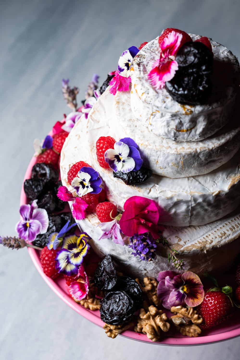 cheese birthday cake with brie, berries, edible flowers and prunes