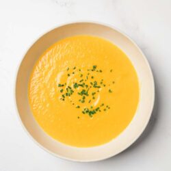 A bowl of Creamy Carrot Ginger Soup in a white bowl ready to serve.