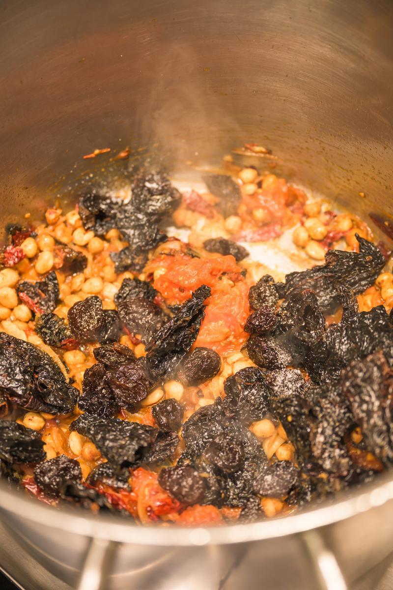 prune mole cooking in a stainless steel pot