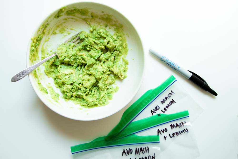 A bowl of mashed avocado mixed with lemon juice ready for small plastic bags to freeze.