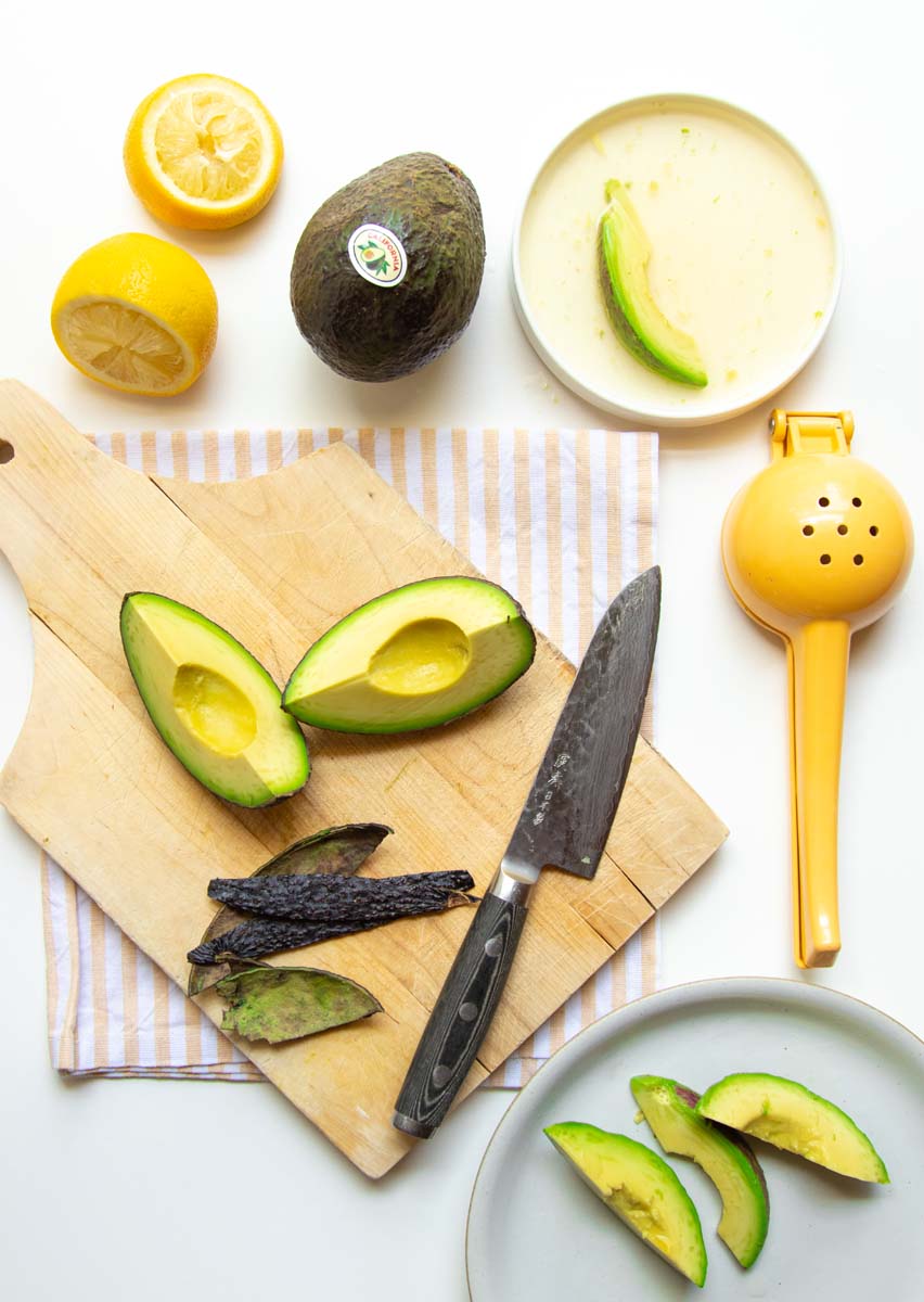 Soaking slices of avocado in lemon juice to prepare for freezing.
